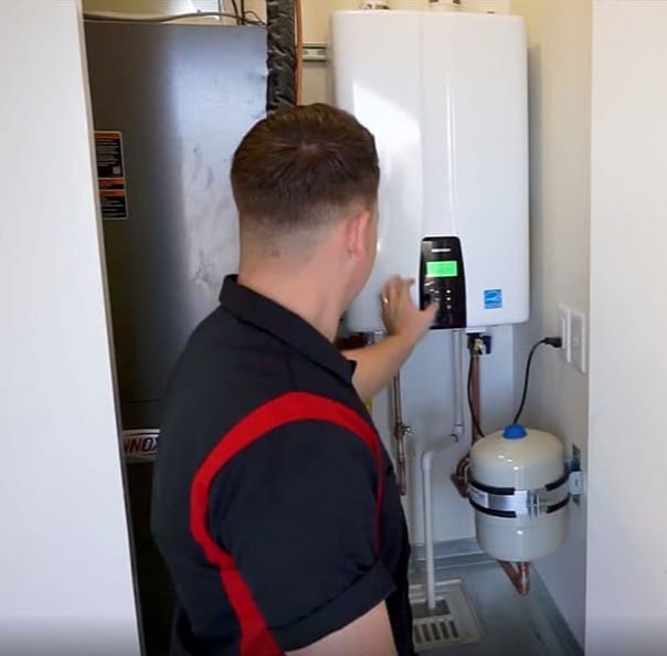 ProSkill plumber checking the control panel on a wall-mounted tankless water heater